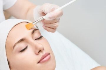 Frau bekommt Peeling auf das Gesicht aufgetragen